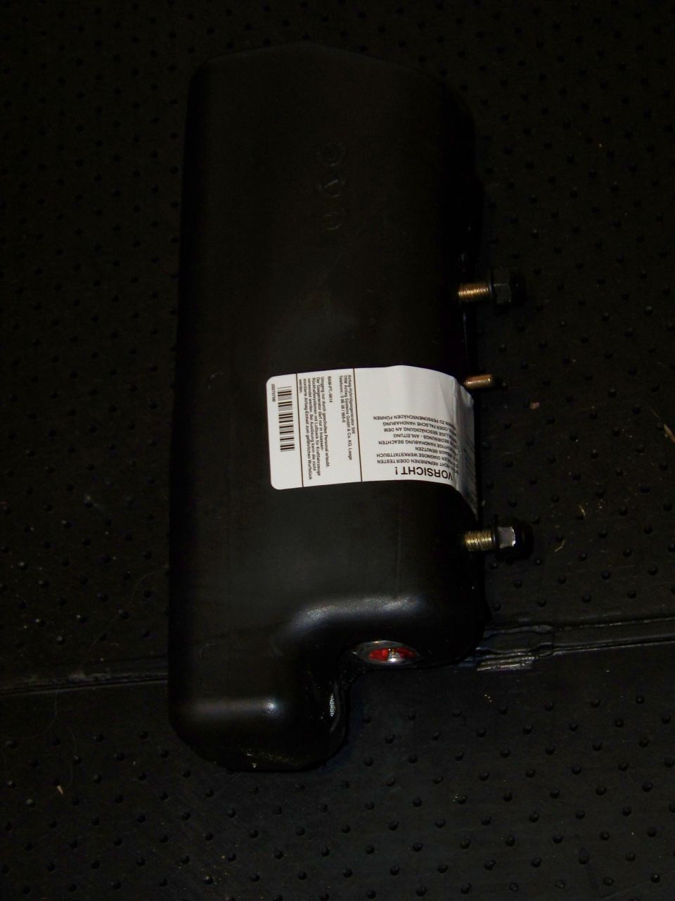 Black cylindrical part with a white label and bolts