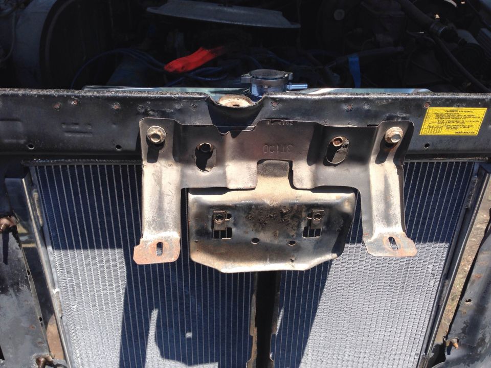 Radiator and metal mounting bracket with bolts, seen from engine bay