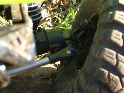 1989 Ford Bronco - A detailed view of the suspension and tire of a remote control car, set against a natural outdoor background.