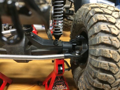 1989 Ford Bronco - The suspension and tire of a remote-controlled vehicle are shown, supported by red jack stands.