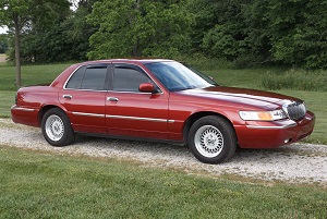 1999 Mercury Grand Marquis - A red 1999 Mercury Grand Marquis is shown from the front three-quarter view on a gravel surface.