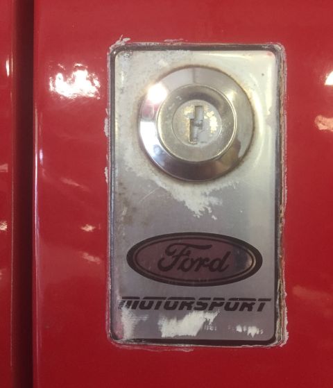 1995 Ford Bronco - Close-up of a Ford Motorsport badge and keyhole on a red vehicle door.
