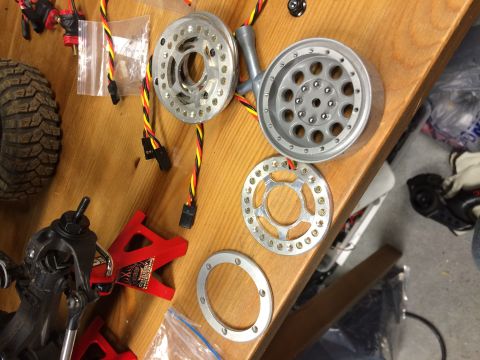 1989 Ford Bronco - Various components for an RC car are laid out on a table, including wheels and tires.