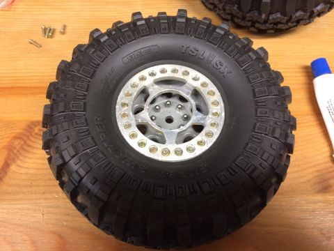 1989 Ford Bronco - Close-up of a scale RC car tire and wheel assembly on a wooden surface.