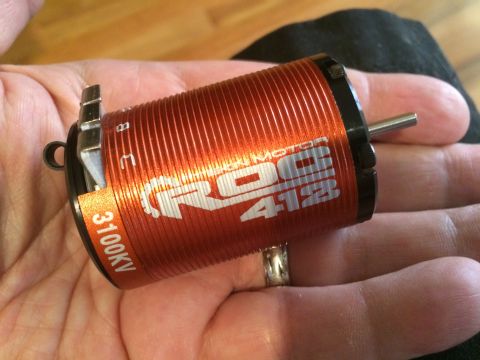1989 Ford Bronco - Close-up of an orange electric motor, identified as ROC 412 with 3100KV rating, held in a hand.