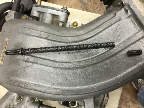 1996 Ford Bronco - Close-up of a braided cable and hex bolt on a gray engine component.