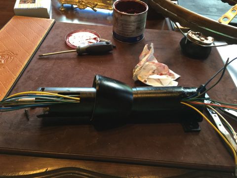 1965 Ford Mustang - A disassembled steering column assembly with exposed wiring lies on a workbench next to tools and a can of grease.