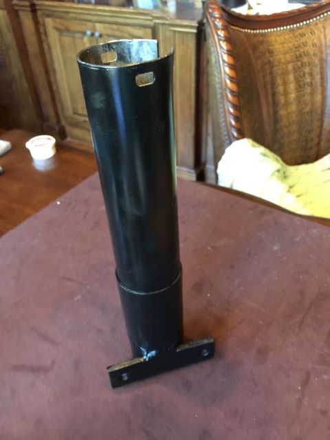 1965 Ford Mustang - This black metal automotive part features a mounting bracket and appears to be a component for a vehicle.