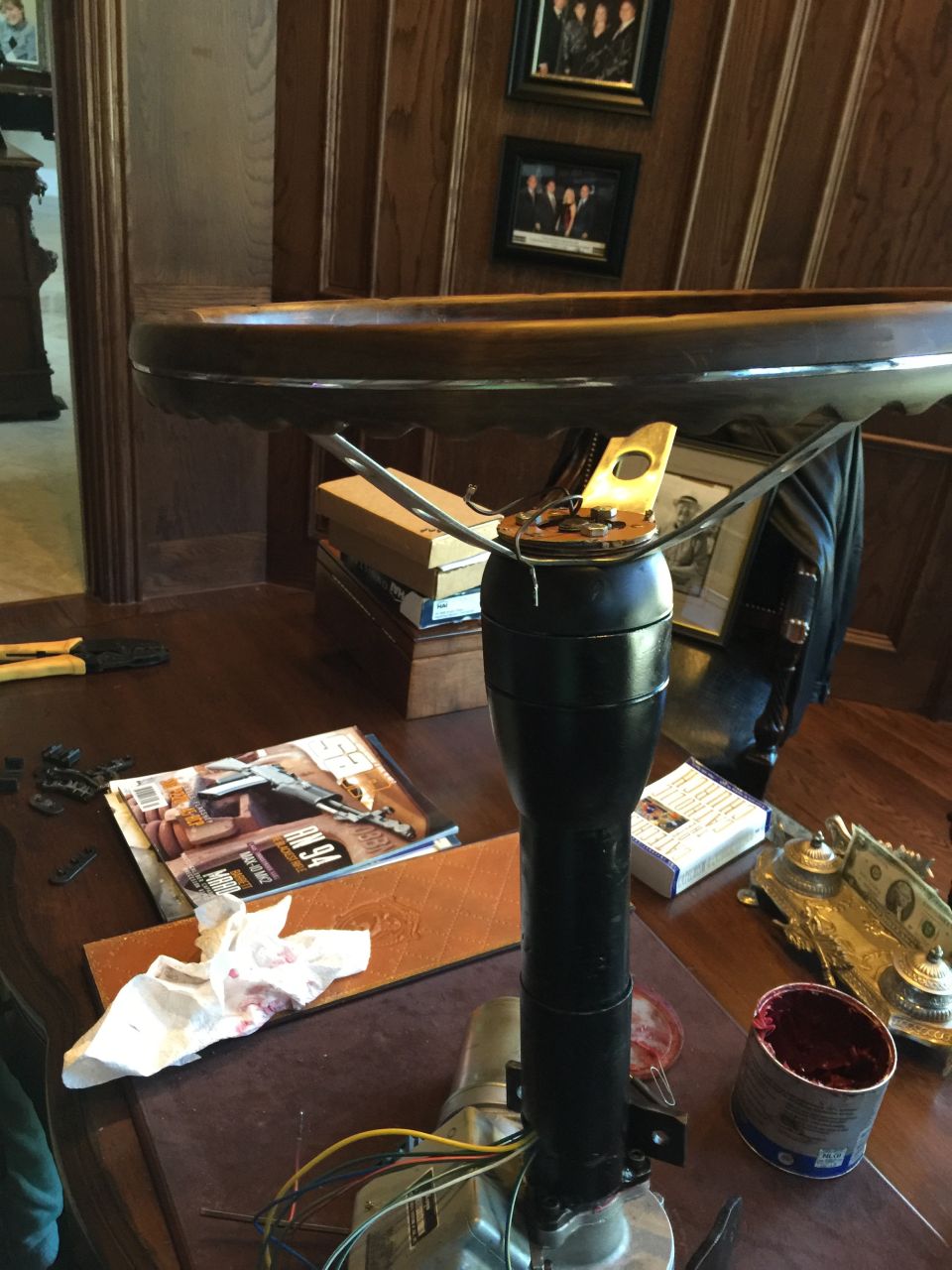 Steering column and wooden steering wheel on a table with tools and a magazine