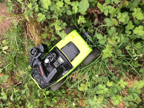 1989 Ford Bronco - Remote control car with controller resting in grass and weeds.