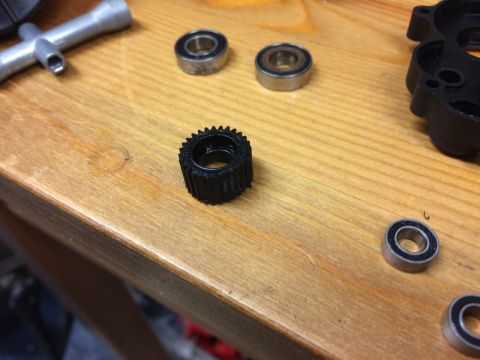1989 Ford Bronco - A close-up view of a small black gear and multiple ball bearings arranged on a wooden table.