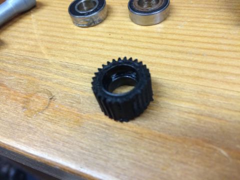 1989 Ford Bronco - A close-up view of a black toothed gear alongside two ball bearings on a wooden surface.