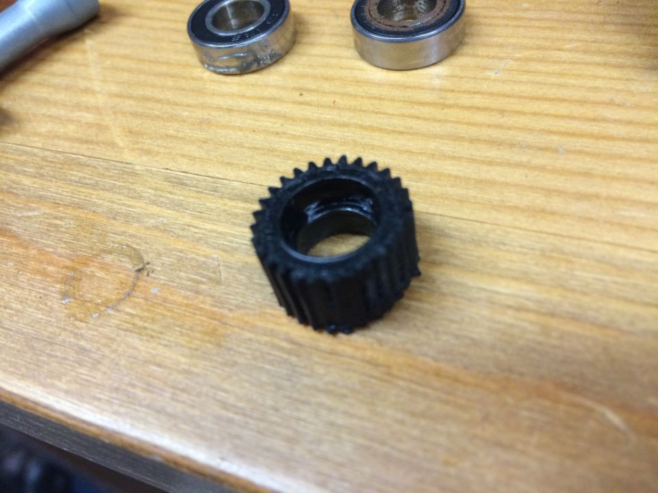 Black toothed gear with two bearings on a wooden surface