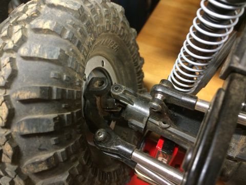 1989 Ford Bronco - Detail of a off-road tire and its suspension system, including linkage and a white coilover shock absorber.