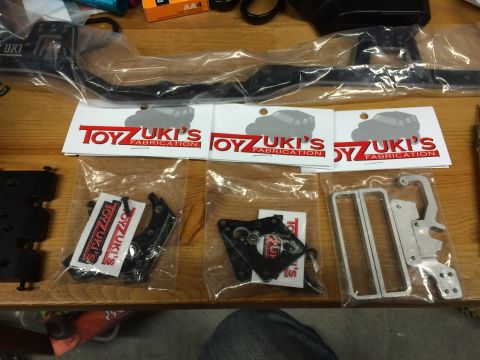 1989 Ford Bronco - Various parts for a remote-controlled vehicle are displayed on a wooden surface, with branding visible on the packaging.
