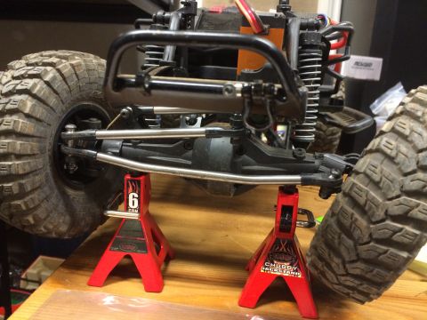 1989 Ford Bronco - Close-up view of an RC car's suspension system and large off-road tires, elevated on jack stands.