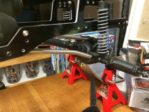 1989 Ford Bronco - Close-up view of a remote control car's chassis, suspension, and axle assembly supported by red jack stands.