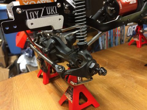 1989 Ford Bronco - Close-up of an RC car's suspension and motor assembly, supported by jack stands.