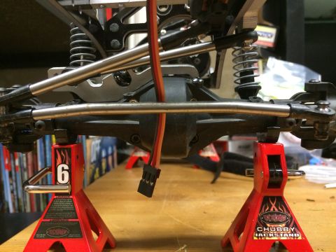 1989 Ford Bronco - The underside of an RC car's suspension and drivetrain is supported by two red jack stands.