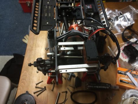 1989 Ford Bronco - The internal components of a remote control car chassis are laid out on a table, with various parts and tools scattered around.