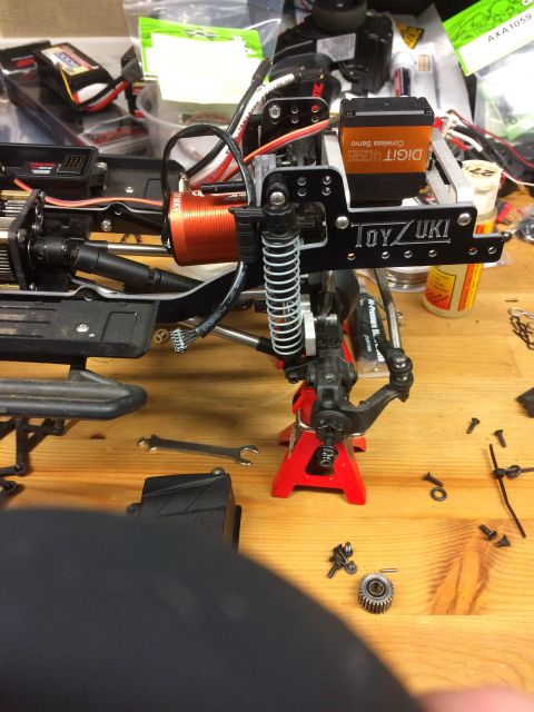 1989 Ford Bronco - Close-up of an RC car's chassis, its motor, servo, and suspension components, with tools nearby.
