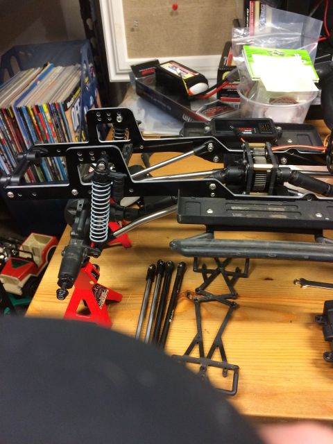 1989 Ford Bronco - RC car chassis assembly with various parts laid out on a wooden surface.