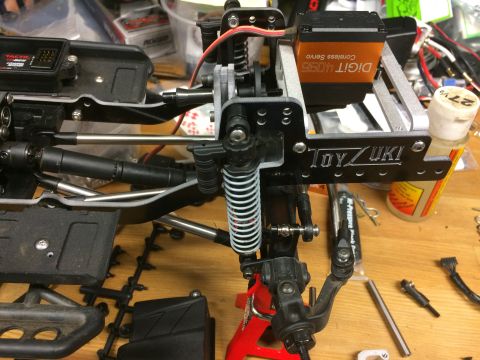 1989 Ford Bronco - Close-up of an RC car's suspension and steering assembly, a servo motor and custom bracket.