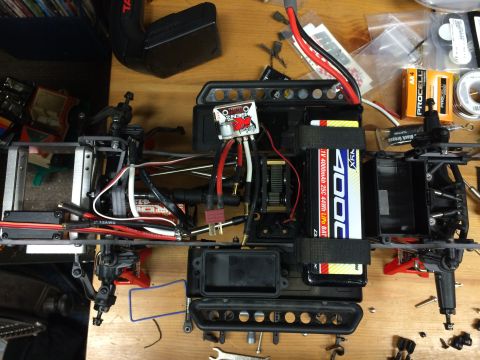 1989 Ford Bronco - The internal components of an RC car are laid out on a workbench, ready for assembly or repair.