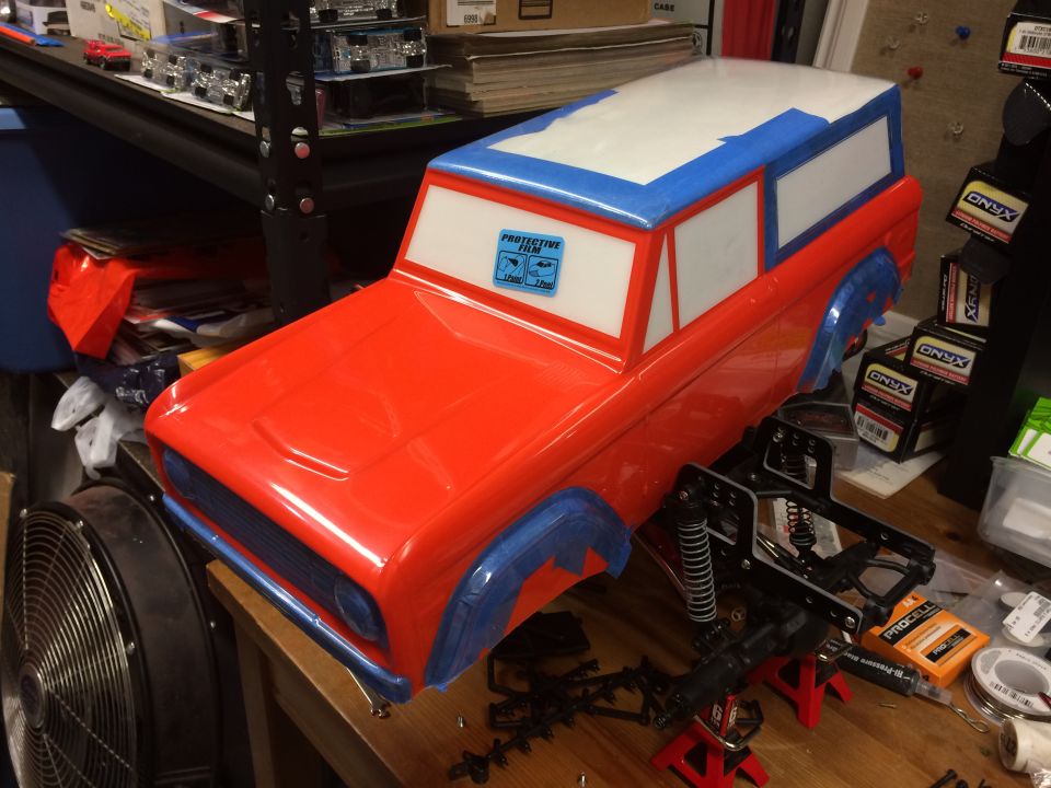 Red and blue RC car body with protective film on windshield, on a workbench