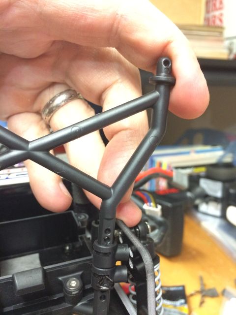 1989 Ford Bronco - A hand is shown holding a black plastic roll cage part, likely for an RC car, with internal components visible in the background.