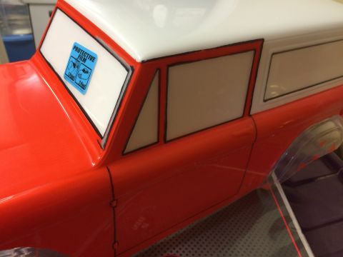 1989 Ford Bronco - Close-up of an RC car body showing painted details and a protective film sticker on the window.