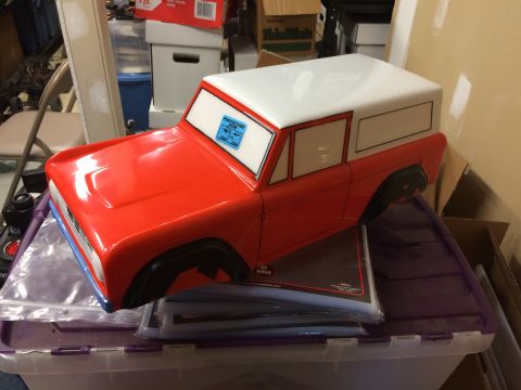 1989 Ford Bronco - A red and white toy Bronco body sits on top of storage bins, with a protective film sticker visible on the windshield.