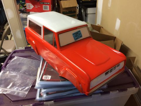 1989 Ford Bronco - A red and white RC car body is displayed on top of a stack of plastic sleeves.