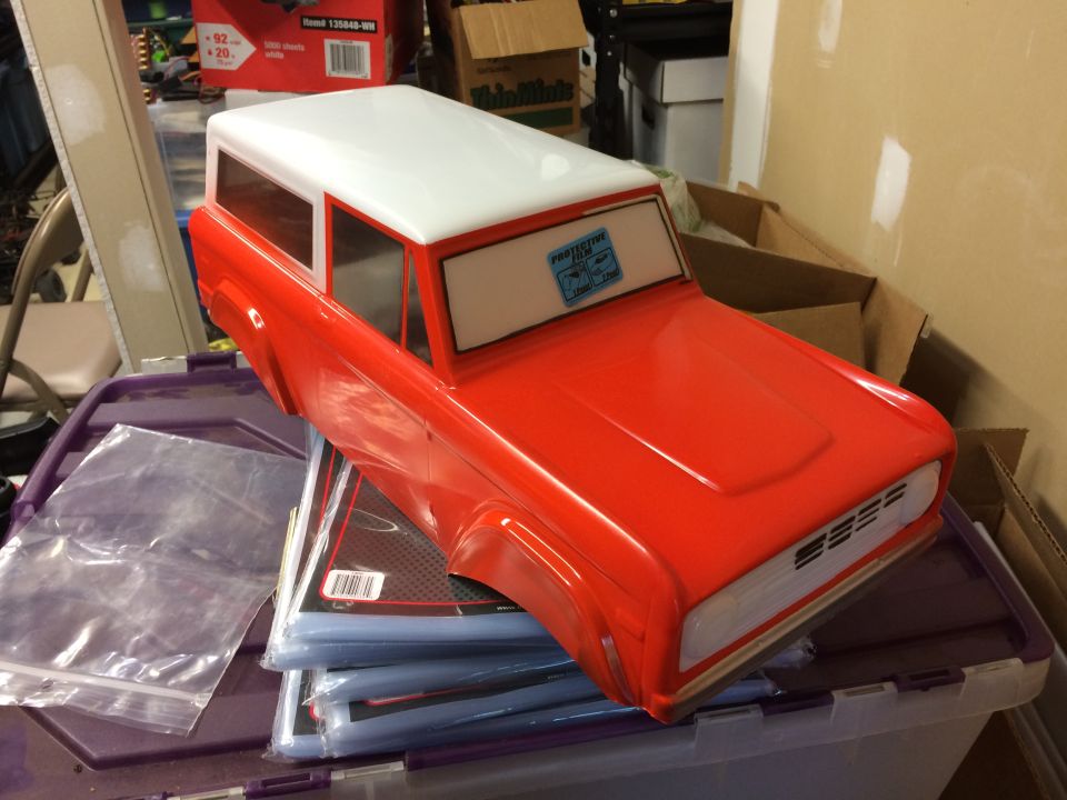 Red RC car body with a white roof sits on plastic sleeves