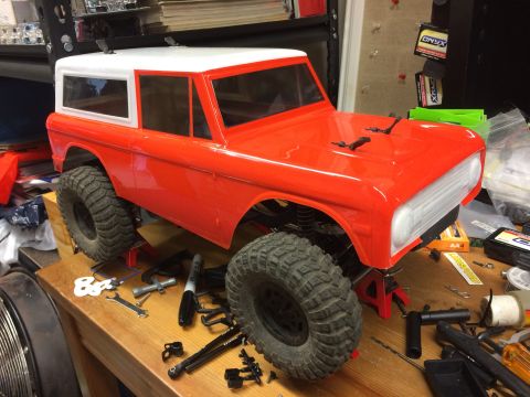 1989 Ford Bronco - RC car body, possibly a Ford Bronco, sits on jack stands surrounded by tools and parts.