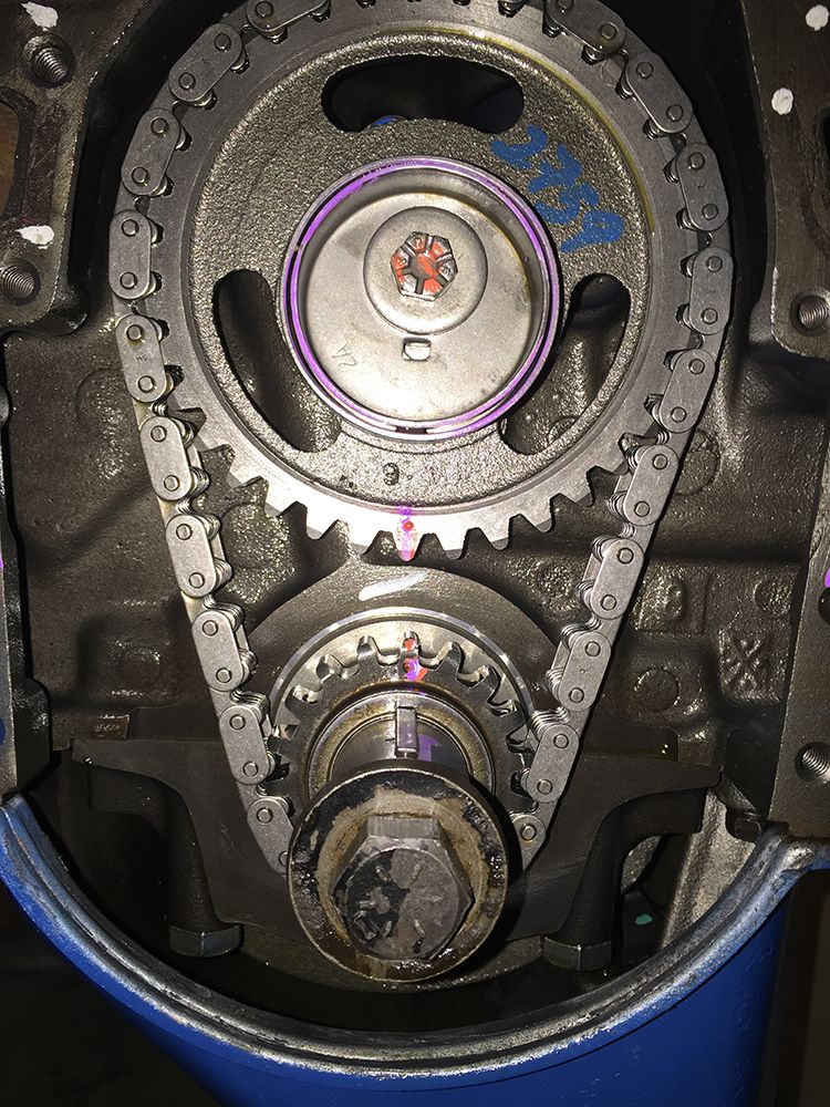 Close-up of engine timing chain and gears with alignment marks.