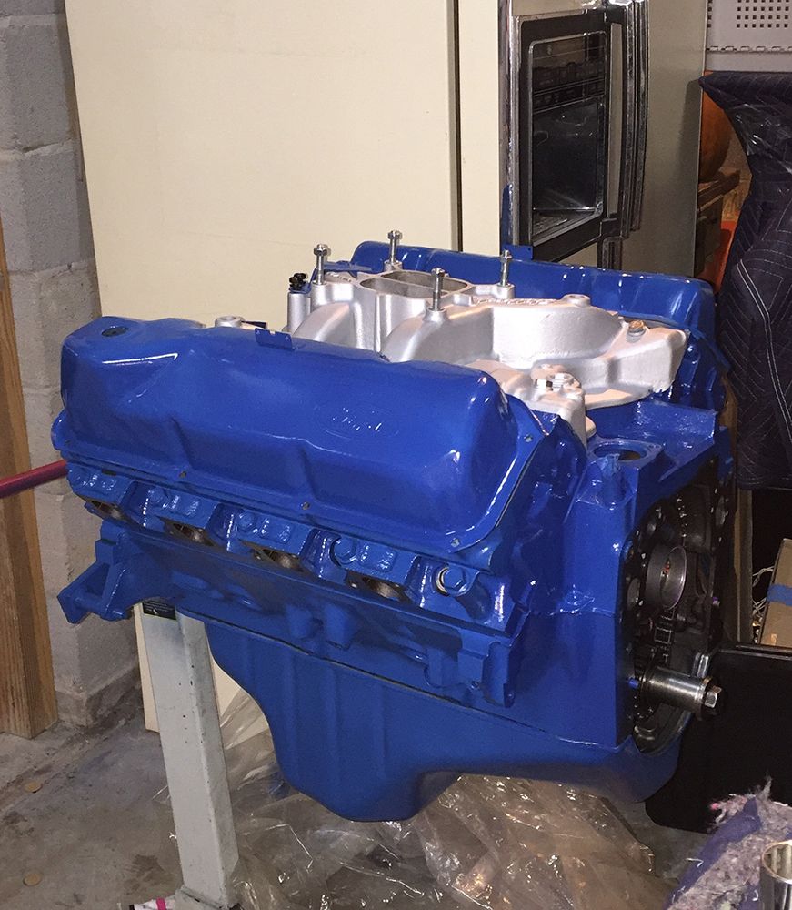 Blue Ford V8 engine on a stand with silver intake manifold.