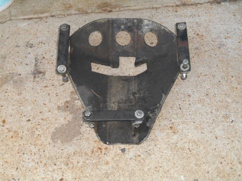 1972 Ford Bronco - A metal skid plate with mounting hardware is shown resting on a concrete surface.