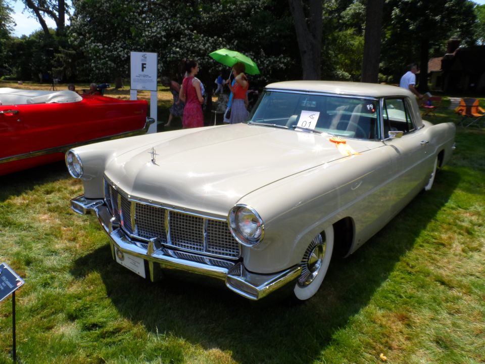 Light-colored vintage coupe with chrome grille and whitewall tires on grass.