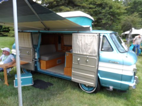 1971 Ford Ranchero - A man sits at a table next to a vintage camper van with its doors and awning open.