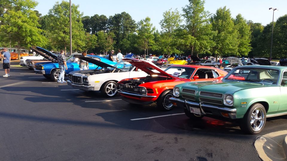 Row of classic cars parked at an outdoor event, hoods up on several