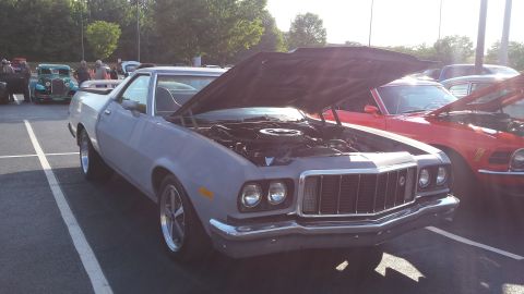 1976 Ford Ranchero - A gray 1976 Ford Ranchero is parked with its hood open, alongside other vehicles at an outdoor gathering.