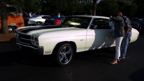 1976 Ford Ranchero - A white coupe with black racing stripes and chrome wheels is parked outdoors.