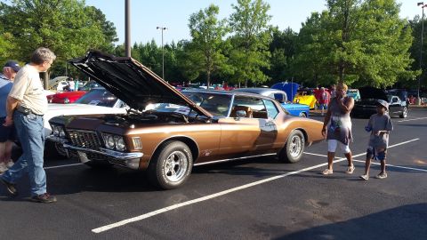 1976 Ford Ranchero - A brown 1971 Buick Riviera is displayed with its hood open at an outdoor car show.