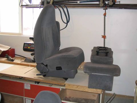 1996 Ford Bronco - A gray car seat and center console are disassembled and placed on a workbench in a workshop.