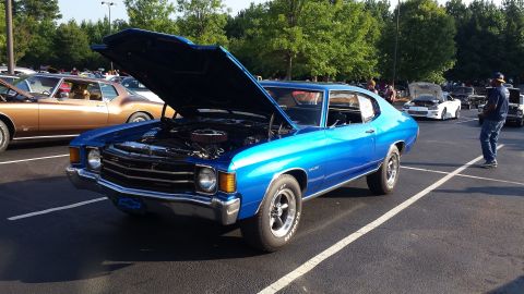 1976 Ford Ranchero - A blue muscle car is displayed with its hood open at an outdoor car show.