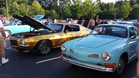 1976 Ford Ranchero - Two classic cars, a gold muscle car and a blue coupe, are displayed at an outdoor event.