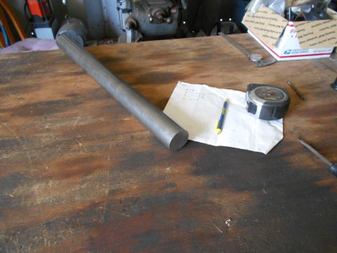 1992 Ford Bronco - A metal shaft with a fluted surface lies on a wooden workbench, accompanied by a tape measure and handwritten notes.