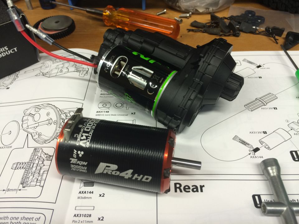 Two electric RC car motors and a gearbox on assembly instructions.
