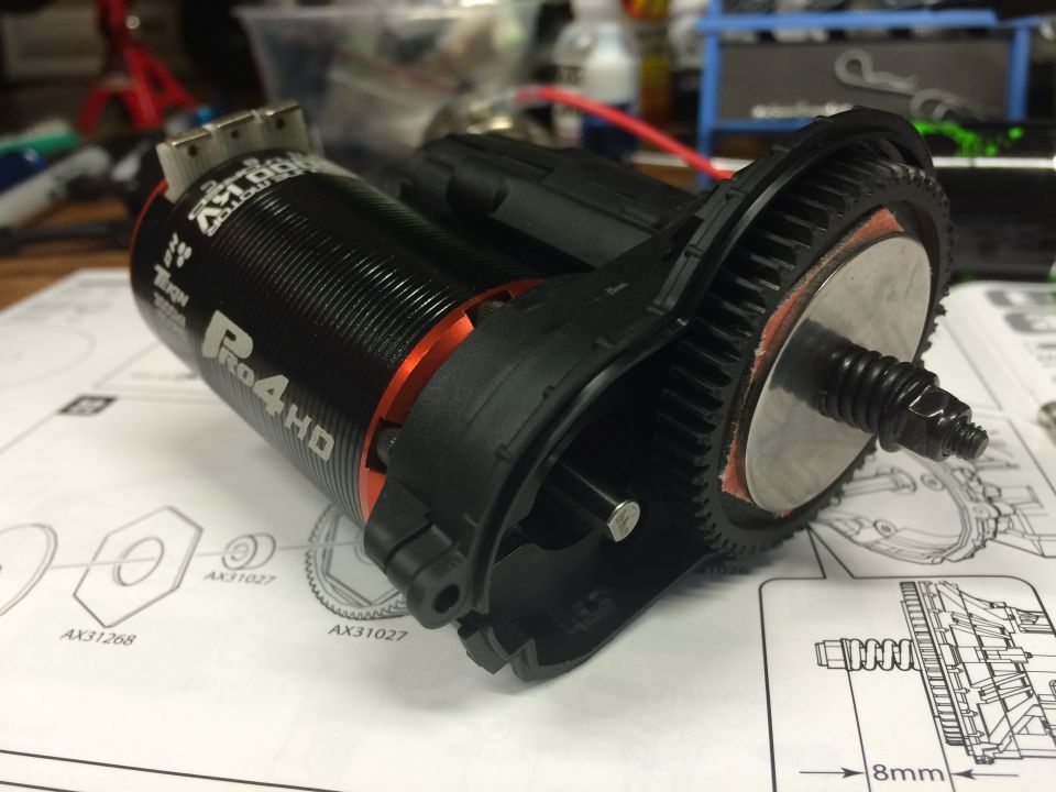 Black electric motor with orange accents and gear housing on a diagram document.
